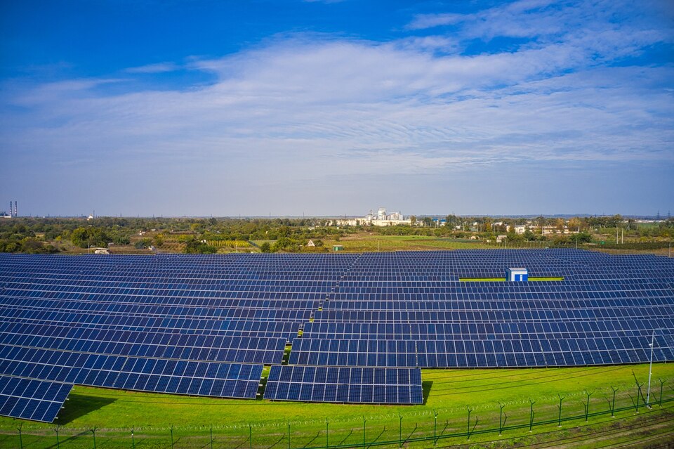 Expansive solar park under clear skies showcasing rows of solar panels generating renewable energy in India.